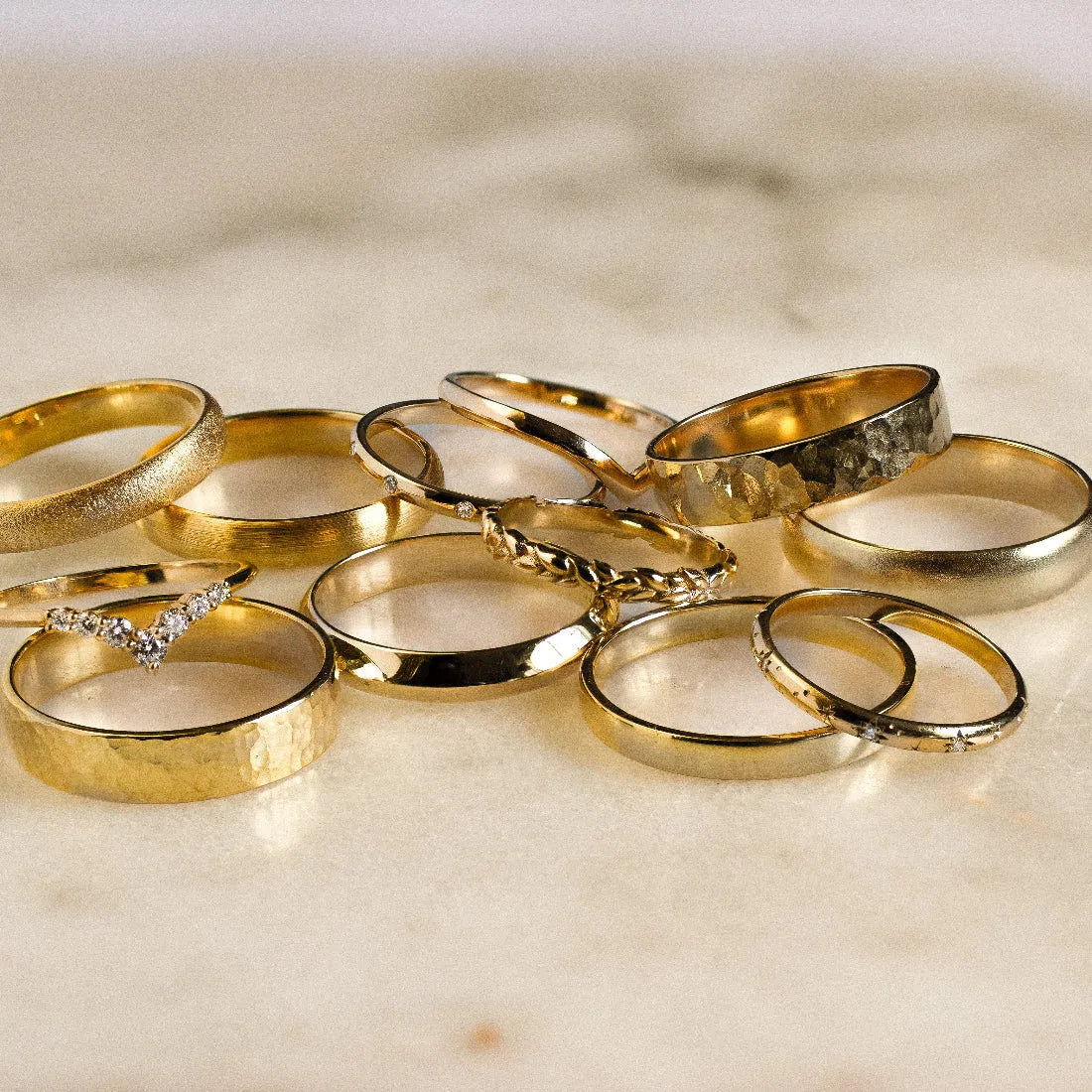 gold wedding rings in different textures on a marble surface