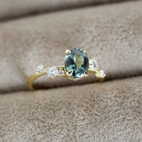 Gold ring with a green gemstone and small diamonds on a beige fabric background