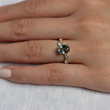 Hand wearing a ring with a green gemstone on a light background