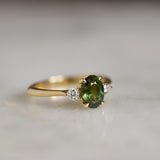 forest green sapphire engagement ring with diamonds on marble surface