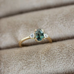 Gold ring with a green gemstone on beige fabric