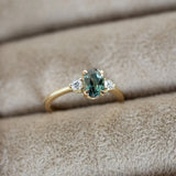 Gold ring with a green gemstone on beige fabric