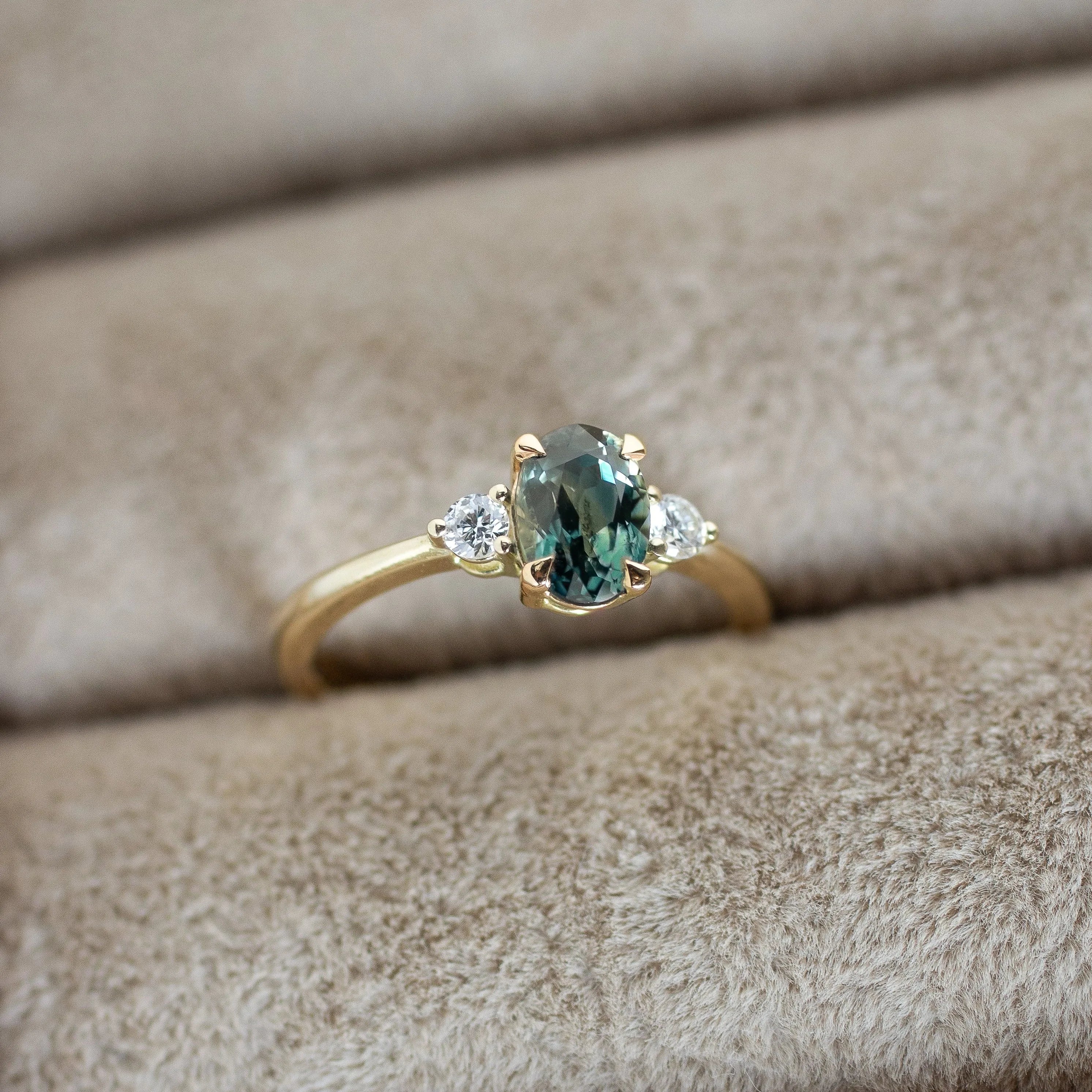 Gold ring with a green gemstone on beige fabric