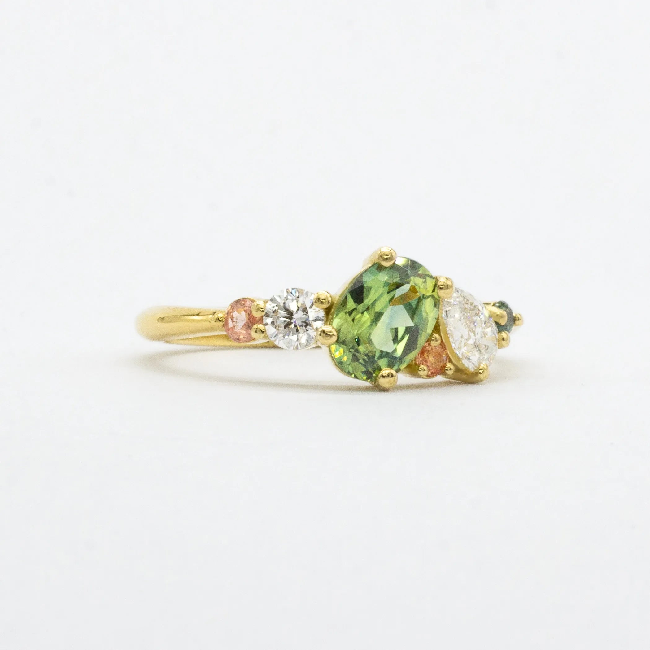 side angle of engagement ring featuring large green sapphire, pink sapphires and diamonds