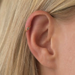 Ear wearing solid gold diamond helix earrings