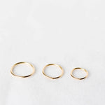 Three cartilage hoop earrings gold rings of different sizes on a white background