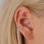 Close-up of a person's ear wearing two gold hoop earrings and conch ear cuff.