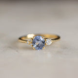 close up of light blue sapphire engagement ring on marble surface