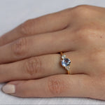 close up of hand wearing cornflower blue sapphire engagement ring with asymmetric diamond cluster