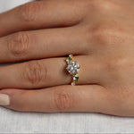 Hand wearing a diamond ring with round diamond and small round sapphires on a light background
