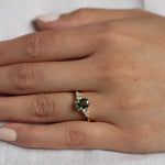 close up of hand wearing green sapphire engagement ring with four diamonds