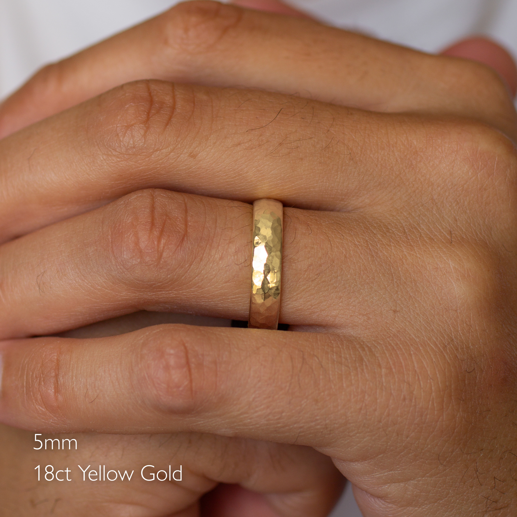 hand wearing 18ct yellow gold chunky hammered wedding ring in d shape
