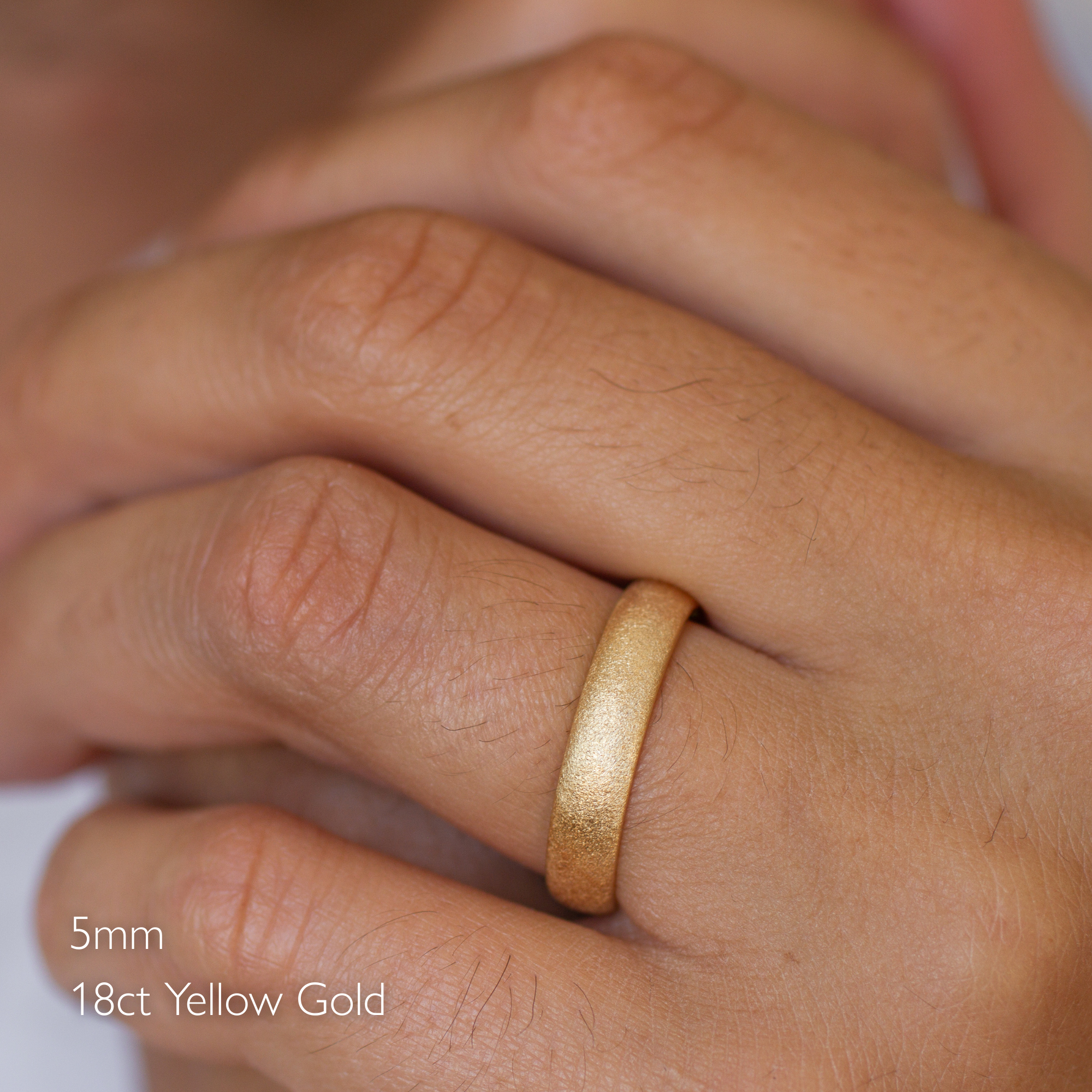 close up of male hand wearing 18ct yellow gold 5mm frosted wedding ring in d shape