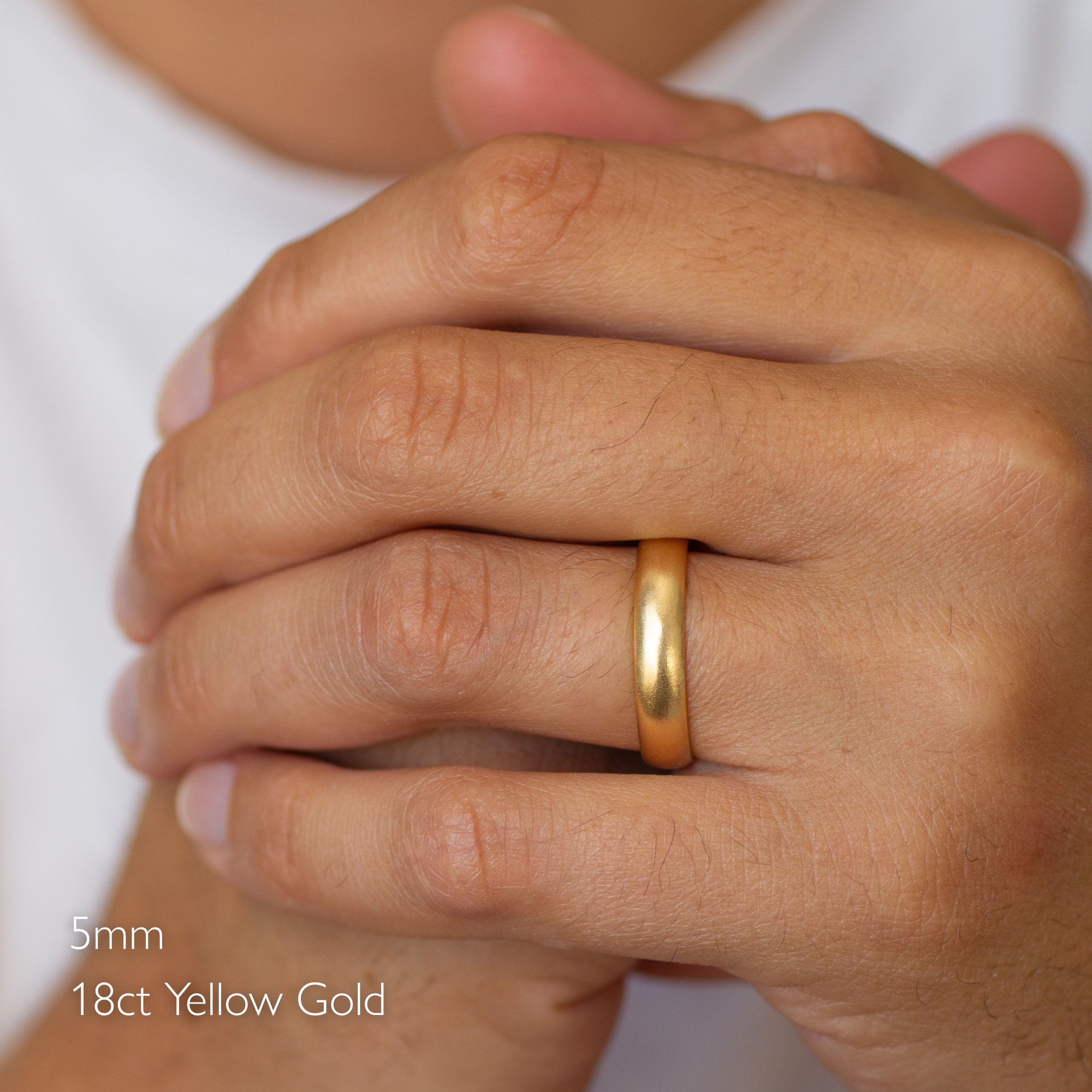 Gold satin wedding ring on a person's finger with '5mm 18ct Yellow Gold' text.