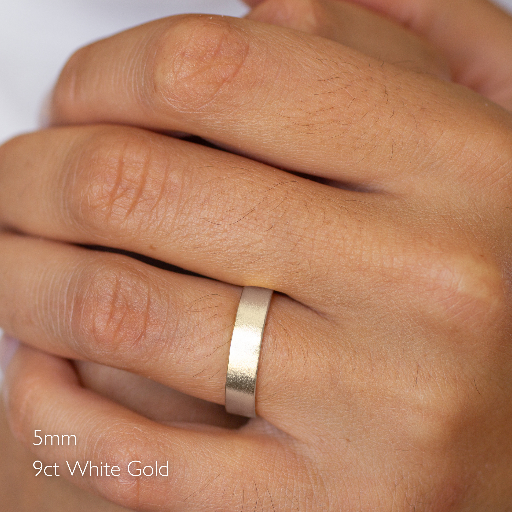 Gold satin flat wedding ring on a hand with '5mm 9ct White Gold' text