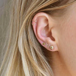 blonde model wearing triangle, bar and pebble gold stud earrings and helix hoops