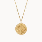 Gold compass necklace with a engraved pendant on a white background