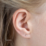 close up of ear wearing 2mm yellow gold diamond stud earrings