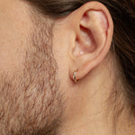 close up of mens ear wearing solid gold huggie hoop earrings