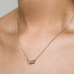 close up of necklace with light pink sapphire and green sapphires being worn