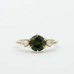 Gold ring with a dark green gemstone and two smaller kite-shaped diamonds on a white background