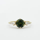 Gold ring with a dark green gemstone and two smaller kite-shaped diamonds on a white background