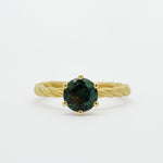 blue/green sapphire engagement ring with gold twisted shank on white background