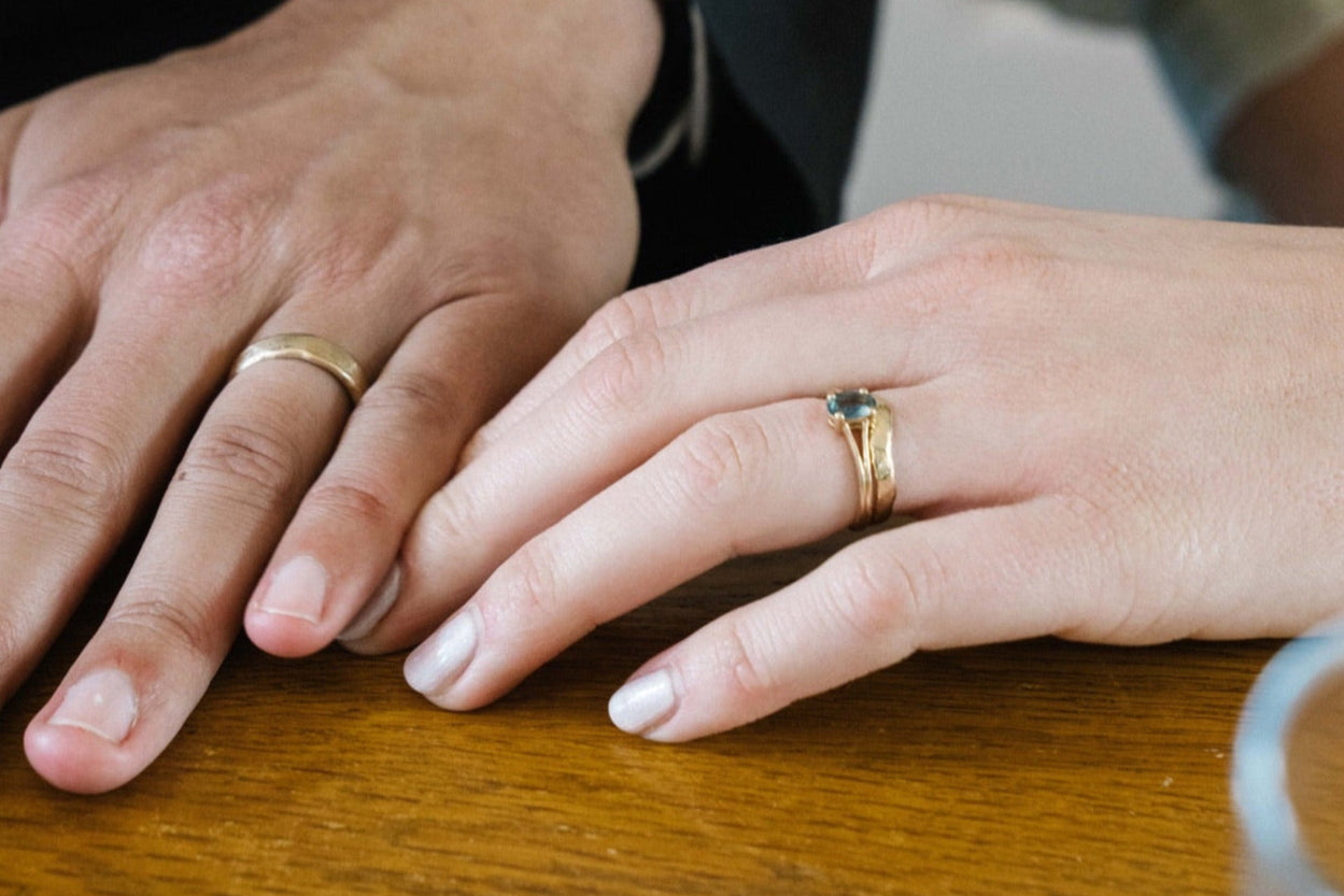 close up of male and female hands wearing gold bespoke wedding rings