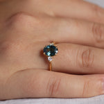 close up of teal sapphire engagement ring on hand