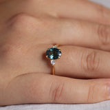 close up of teal sapphire engagement ring on hand