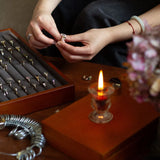 hands comparing two engagement rings, sat infront of an open box of engagement rings