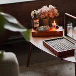 engagement rings in a box on a table with candle, water, flowers and ring sizing tool