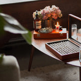engagement rings in a box on a table with candle, water, flowers and ring sizing tool