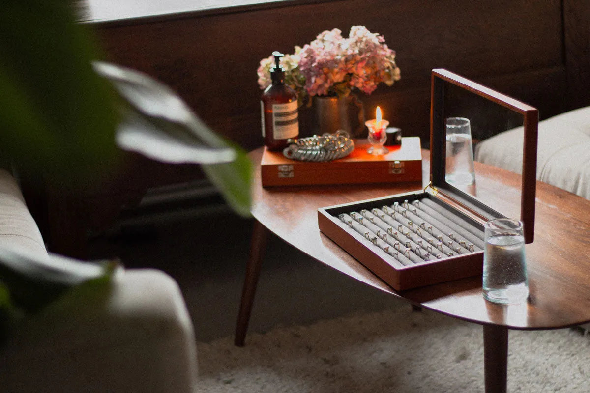 engagement rings in a box on a table with candle, water, flowers and ring sizing tool