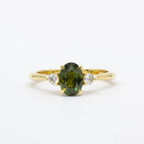 Gold ring with a forest green sapphire and smaller diamonds on a white background
