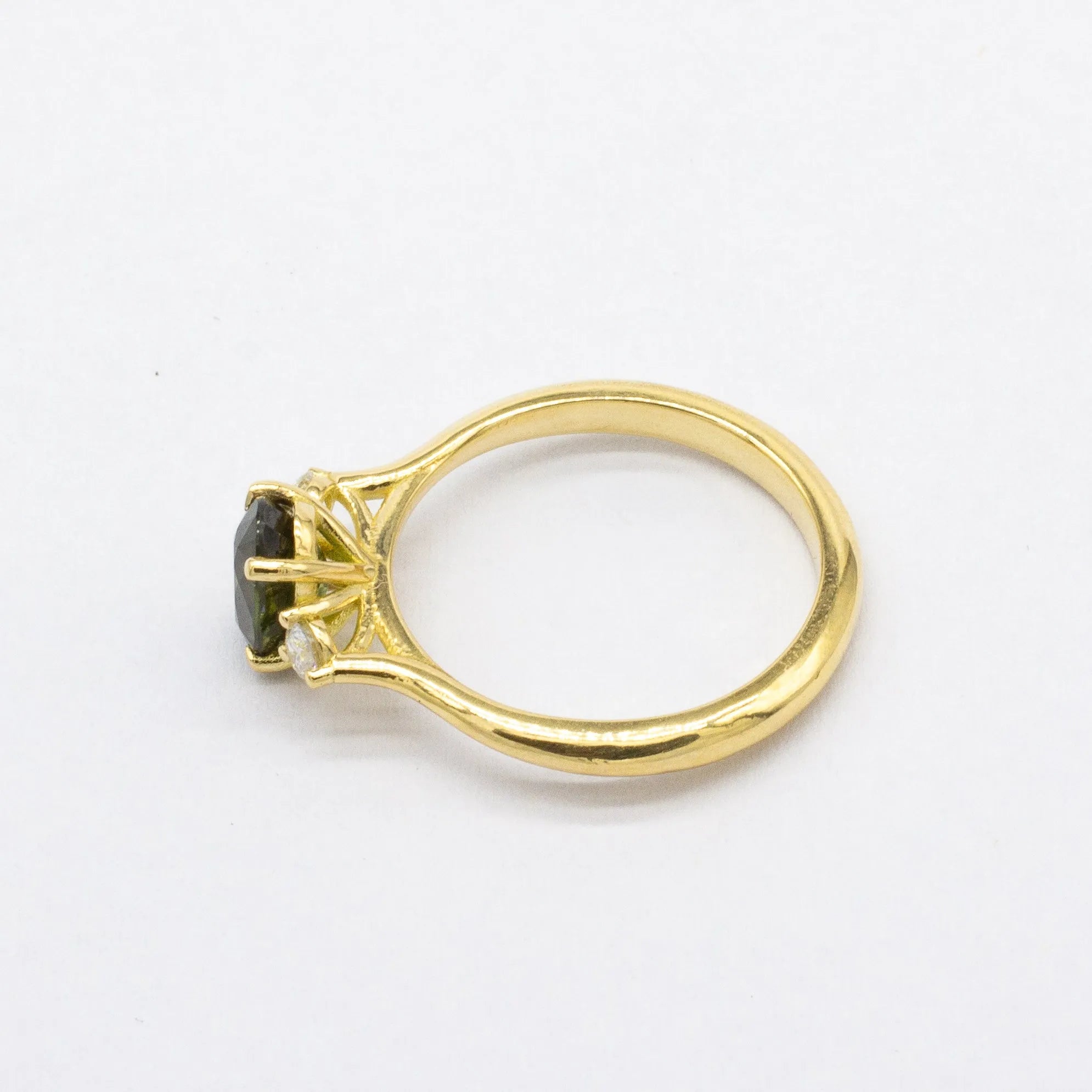 Gold ring with a central forest green sapphire on a white background