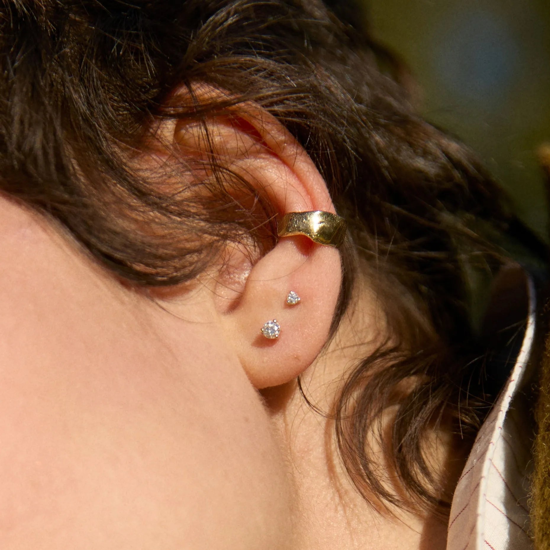 close up of ear wearing lucky gold ear cuff and diamond stud earrings