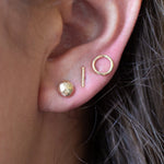 Model wearing pebble, bar and circle studs in solid gold
