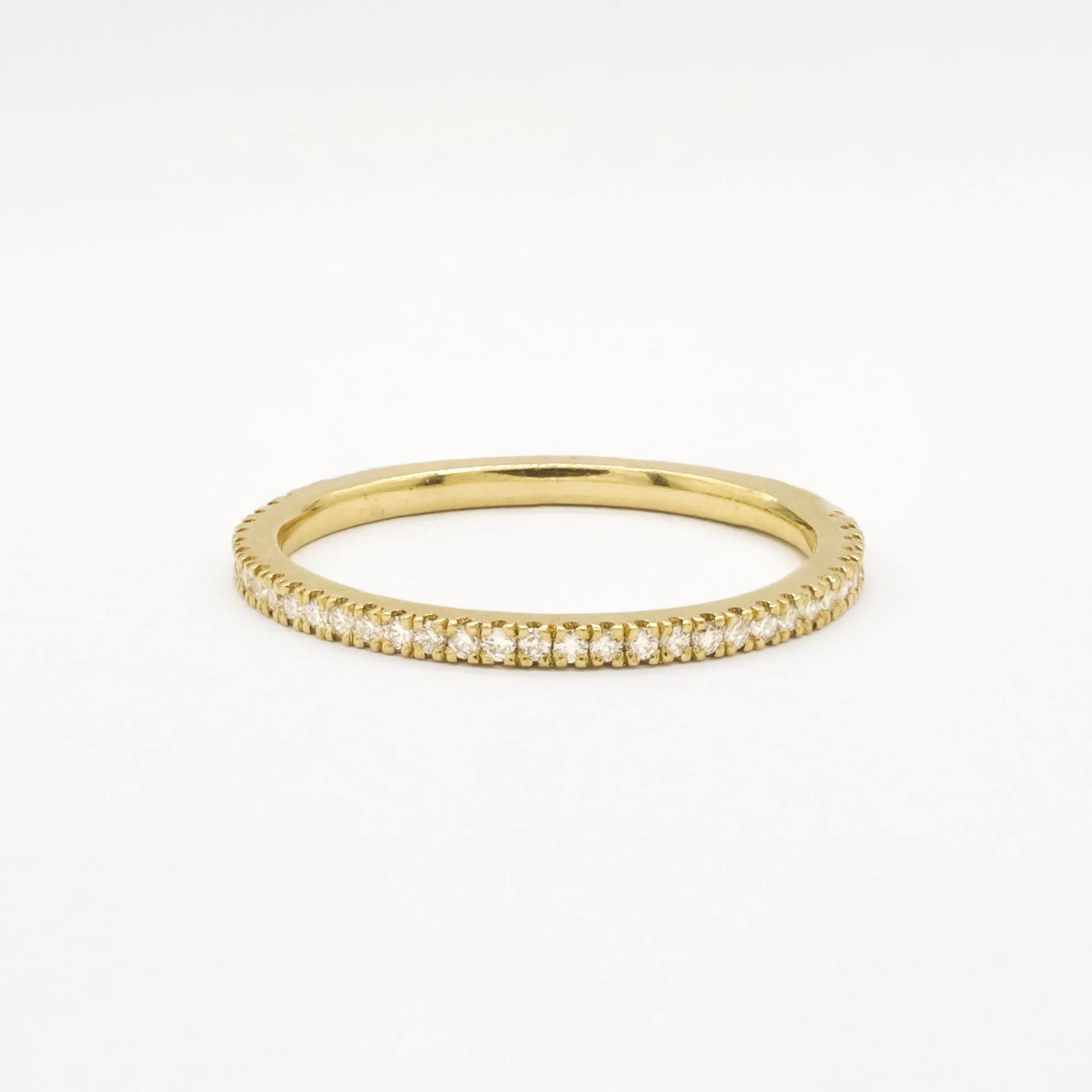 Gold eternity wedding ring with 1mm small diamonds on a white background