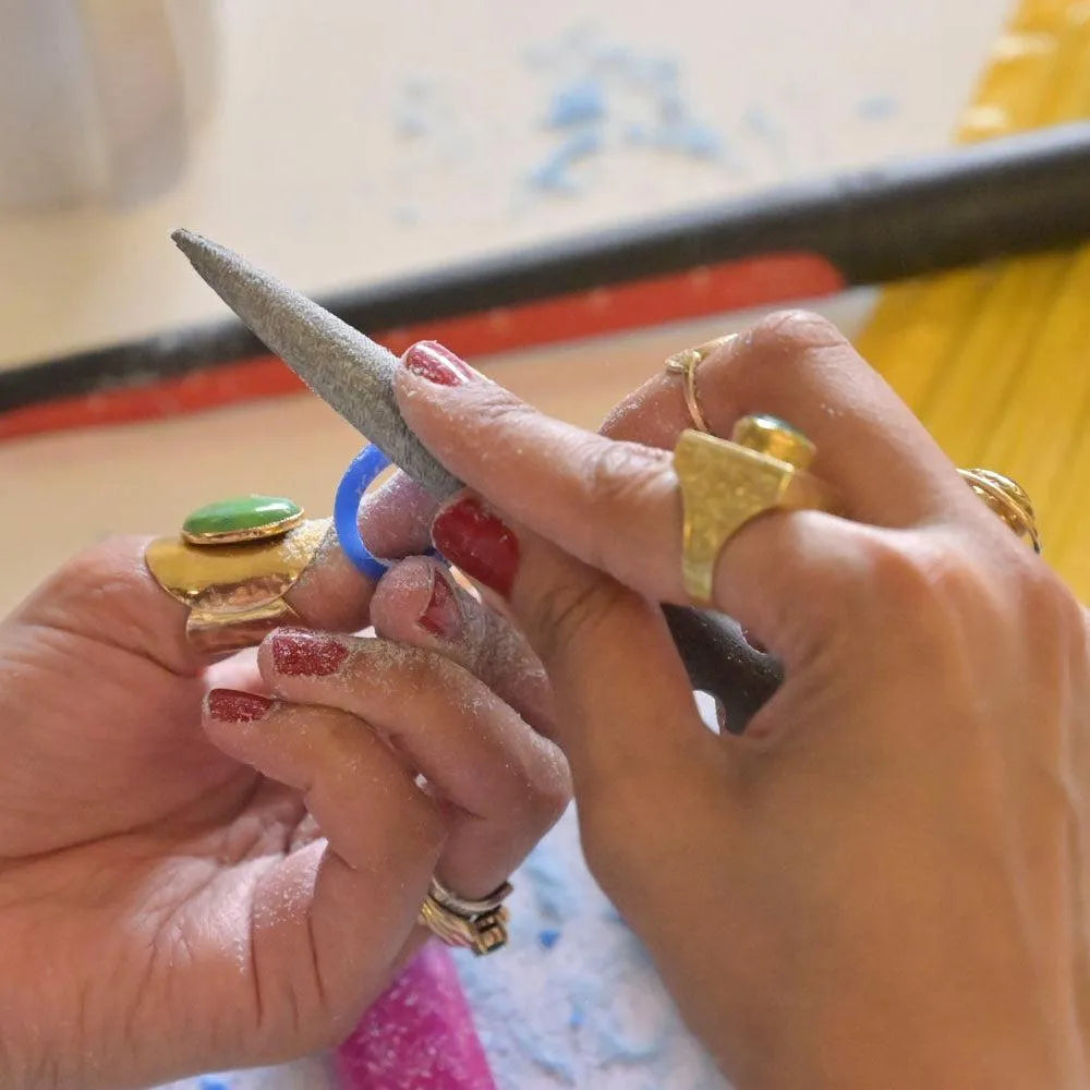 hands wearings chunky rings filing a wax mould made at our jewellery workshops in London