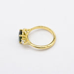 Gold ring with a green gemstone and a diamond on a white background