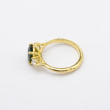 Gold ring with a green gemstone and a diamond on a white background
