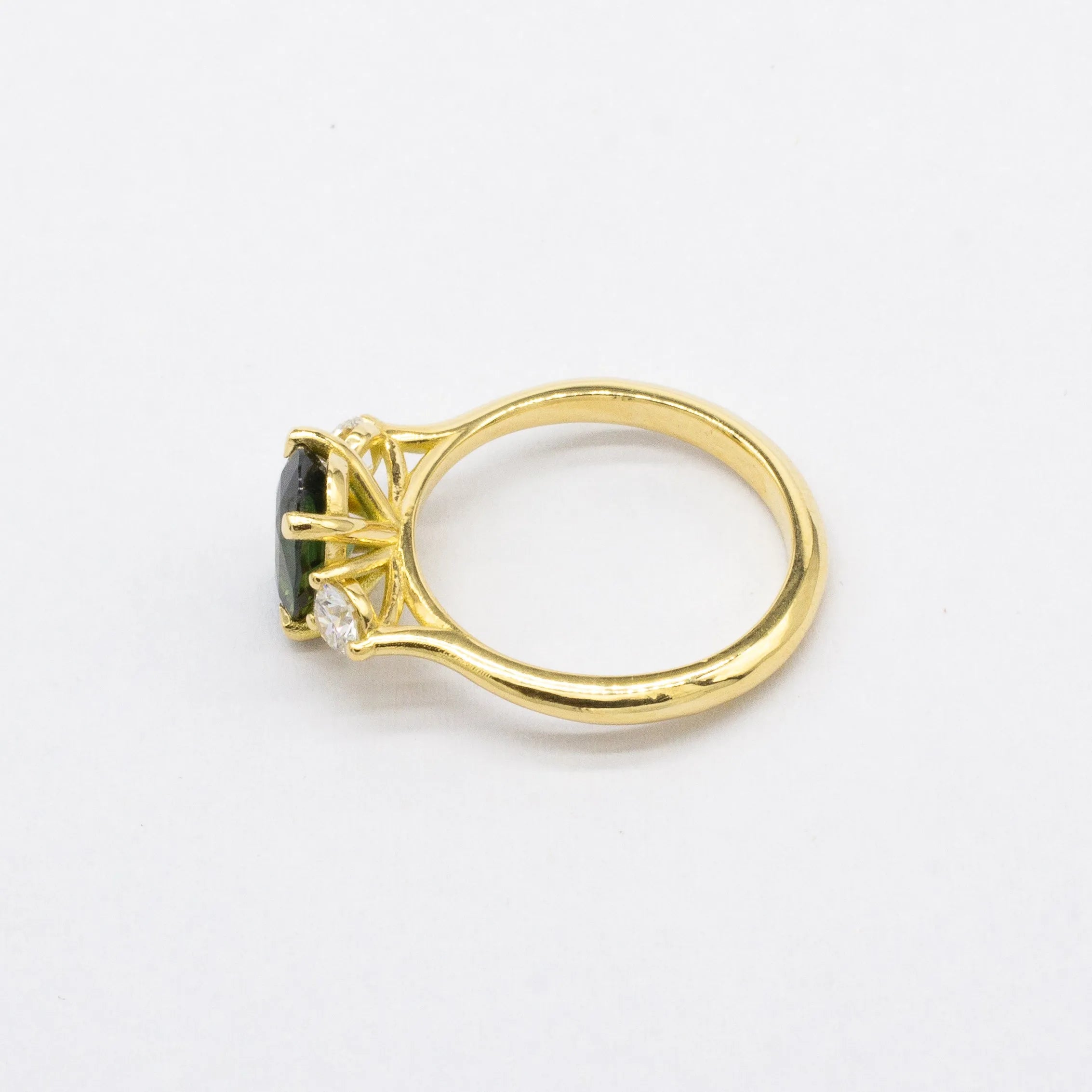 Gold ring with a green gemstone and a diamond on a white background