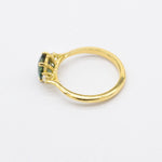 high-set engagement ring with a green gemstone on a white background