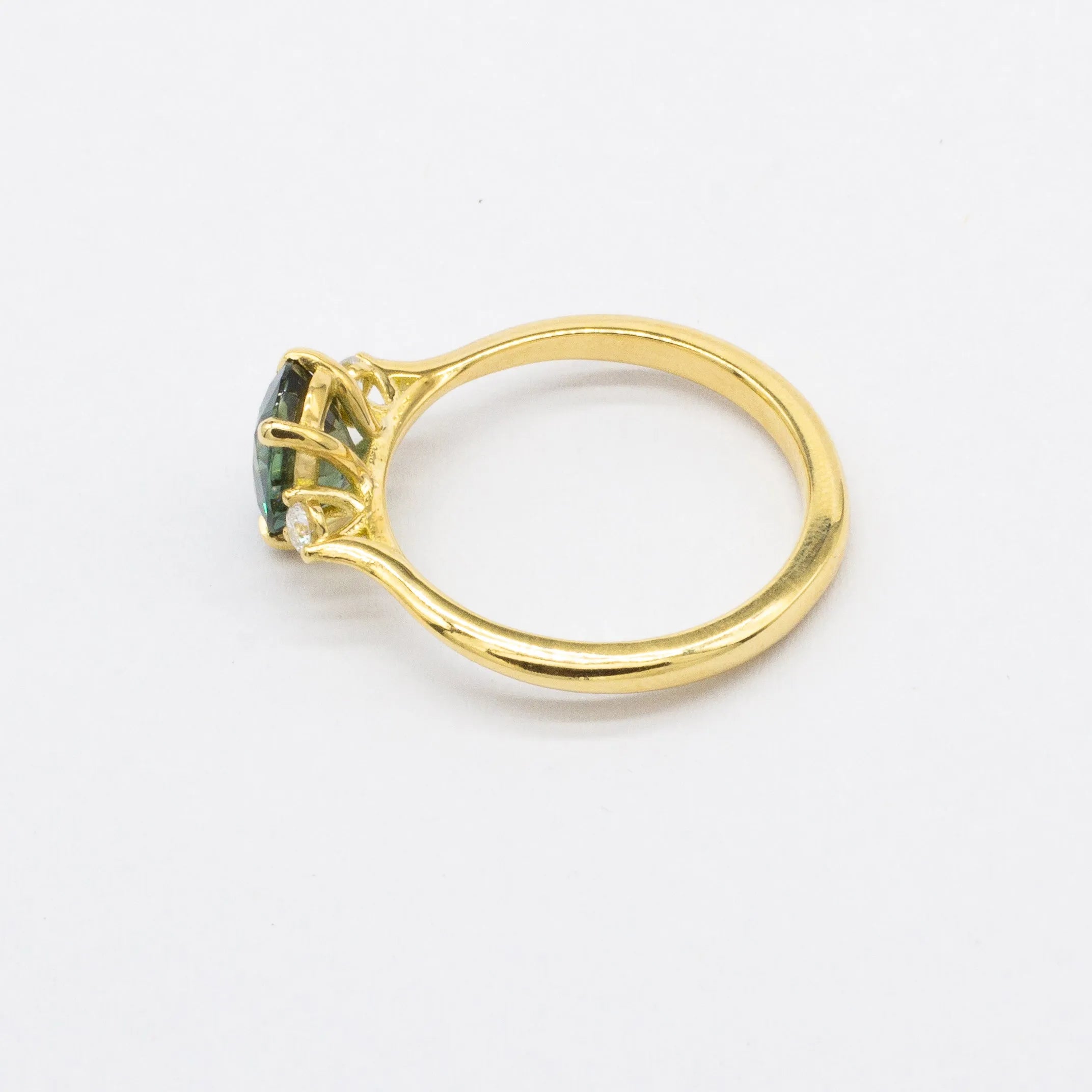 high-set engagement ring with a green gemstone on a white background