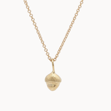 Gold necklace with a small acorn pendant on a white background