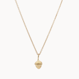 Gold necklace with a small acorn pendant on a white background