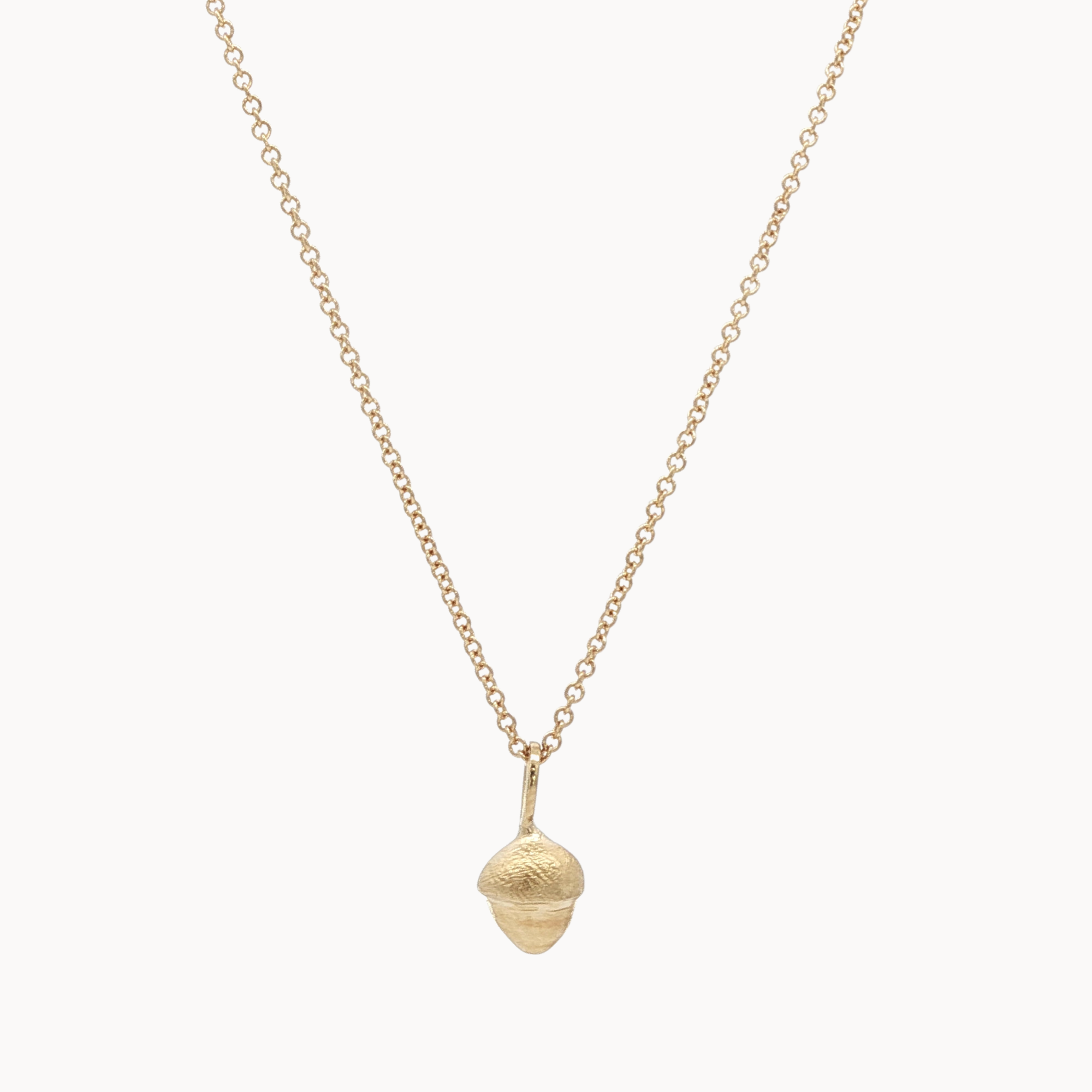 Gold necklace with a small acorn pendant on a white background