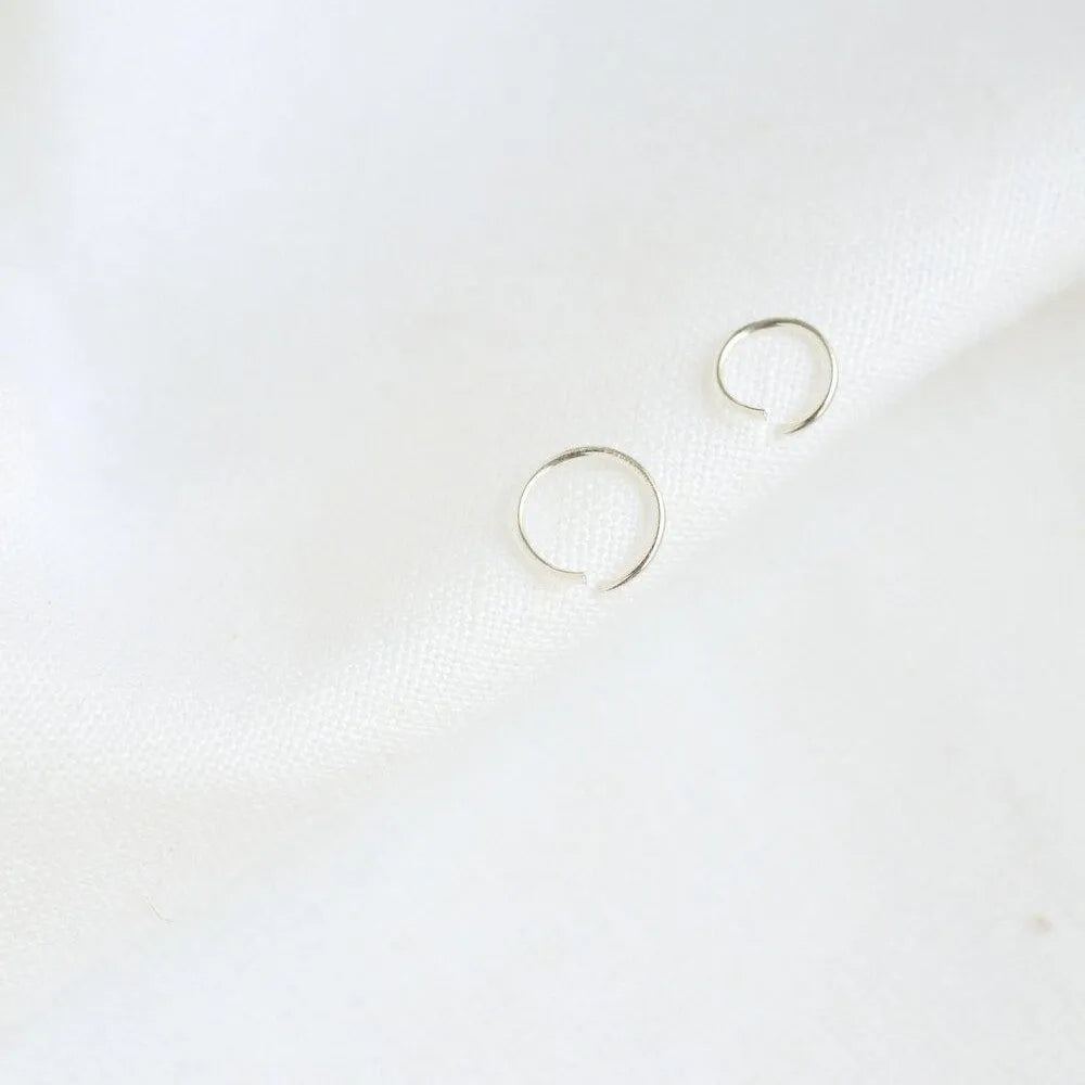 Pair of silver helix hoop earrings on a white background