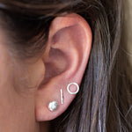 Close up of brunette models ear wearing pebble, bar and circle silver stud earrings